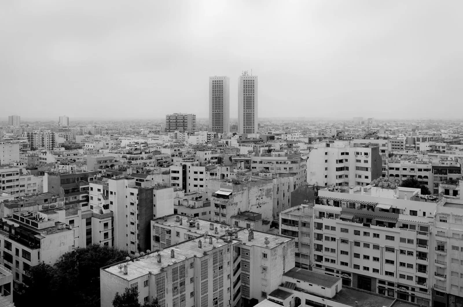 Vue aérienne en noir et blanc de Casablanca, avec les deux tours du Twin Center qui dominent les immeubles du centre-ville dans la brume