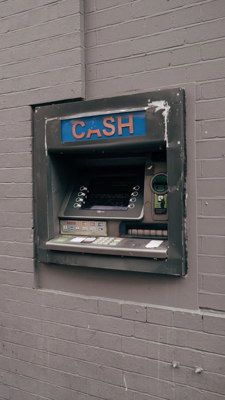Distributeur automatique de billets encastré dans un mur de briques, sous une enseigne CASH lumineuse