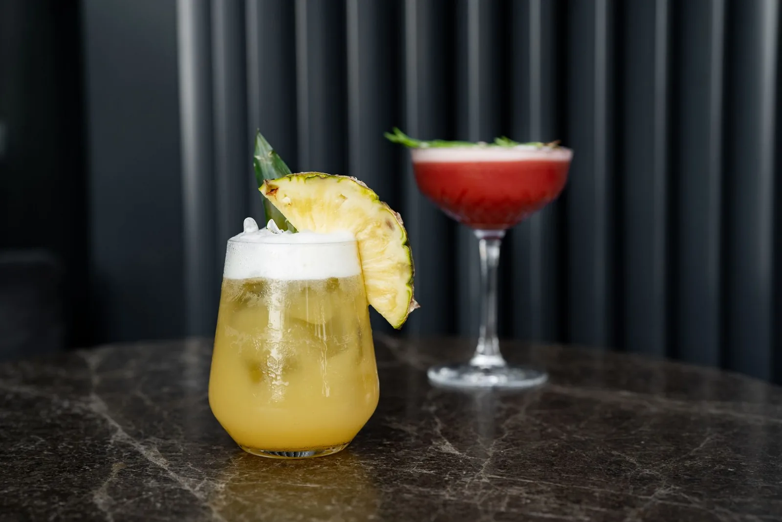 Deux cocktails soignés posés sur une table en marbre dans un bar-lounge tamisé à Marrakech