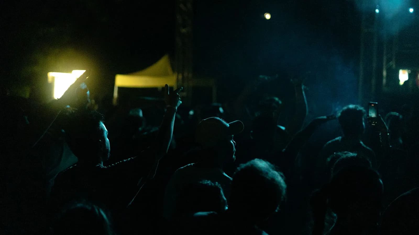 Foule sur le dancefloor d'un club, mains levées sous les lumières bleues, ambiance nocturne