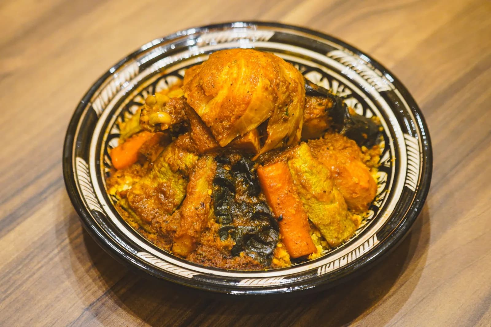 Couscous marocain aux sept légumes servi dans un plat en terre cuite peint à Marrakech