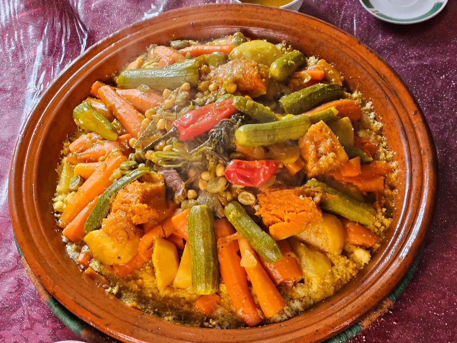 Couscous marocain aux sept légumes servi en dôme dans un grand plat en terre
