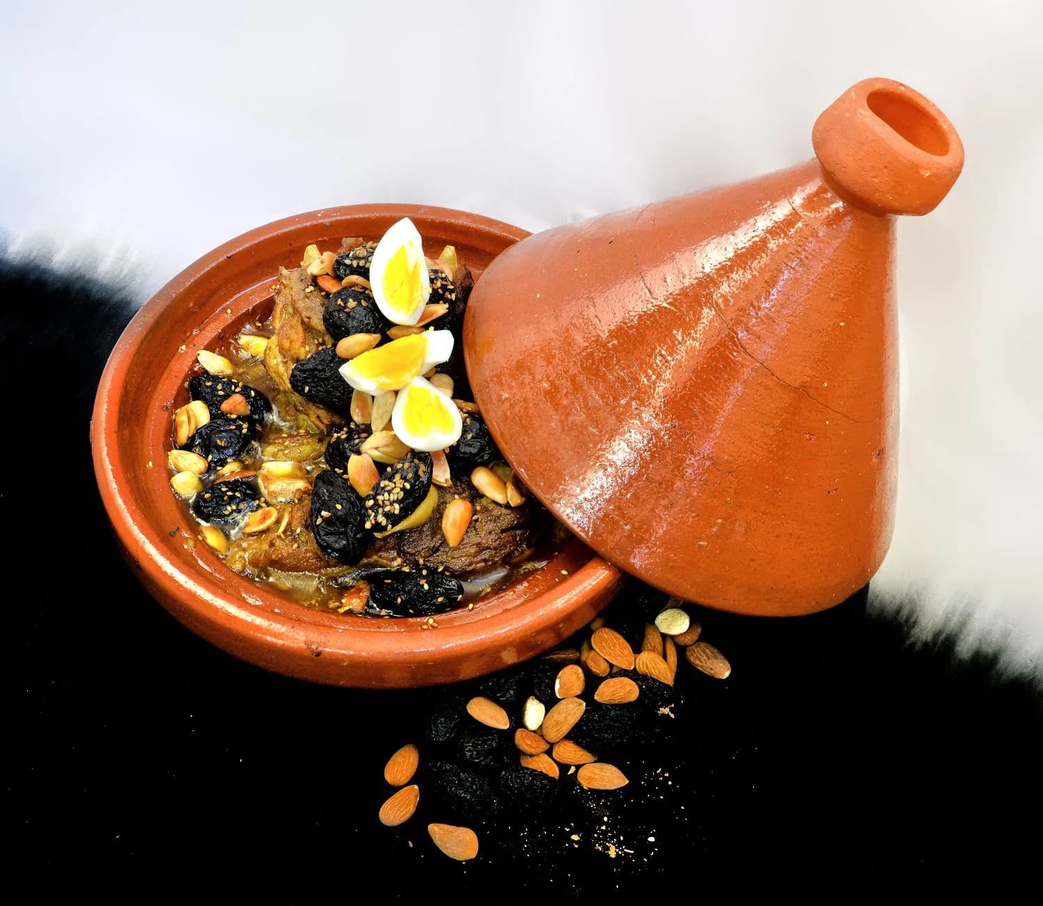 Tajine marocain d'agneau aux pruneaux, amandes et œufs, dans son plat en terre cuite