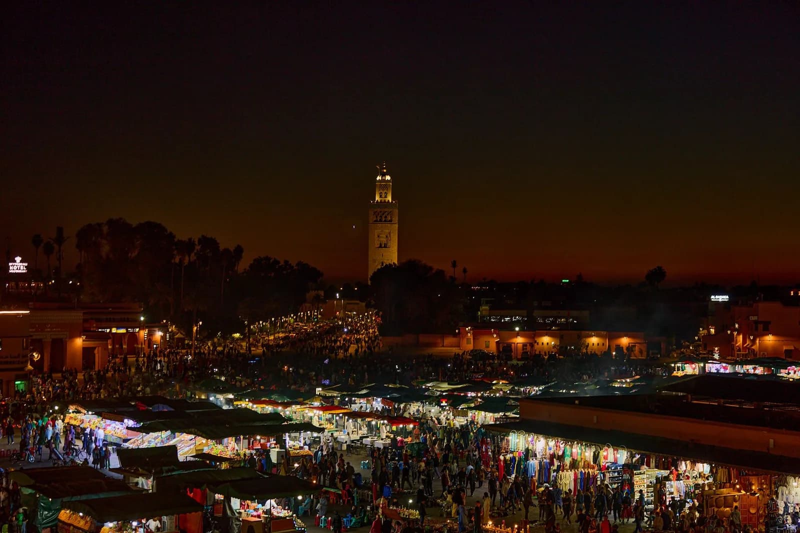 La place Jemaa el-Fna à Marrakech la nuit, illuminée, avec la Koutoubia et la foule des stands