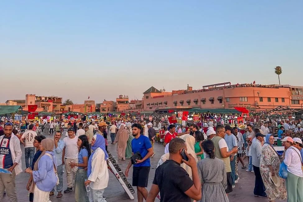 Foule de promeneurs et de visiteurs sur la place Jemaa el-Fna à Marrakech au coucher du soleil, devant les stands et les toits