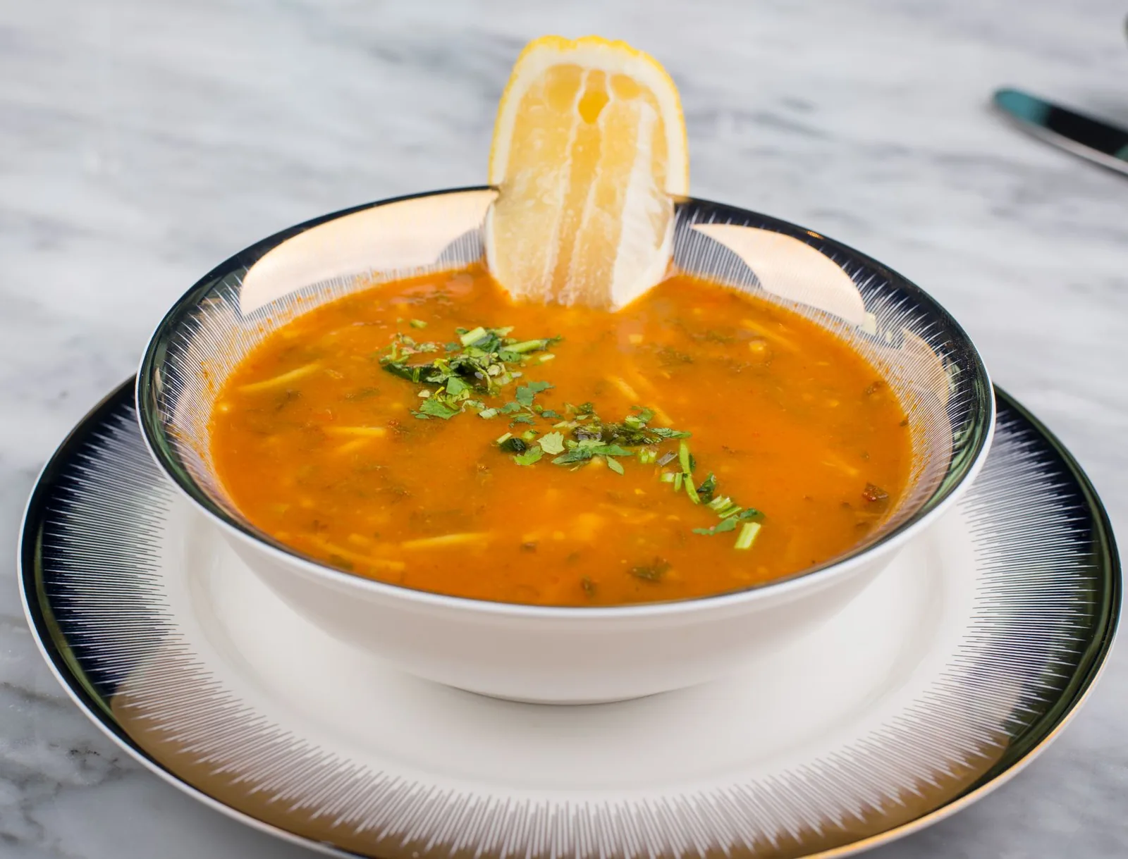 Bol de harira marocaine, soupe de tomate, pois chiches et coriandre servie au ftour avec un quartier de citron