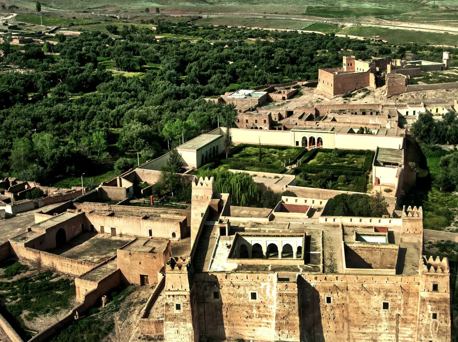 Vue aérienne de la médina de Marrakech, ses murs et bâtiments de terre ocre au pied du Haut Atlas