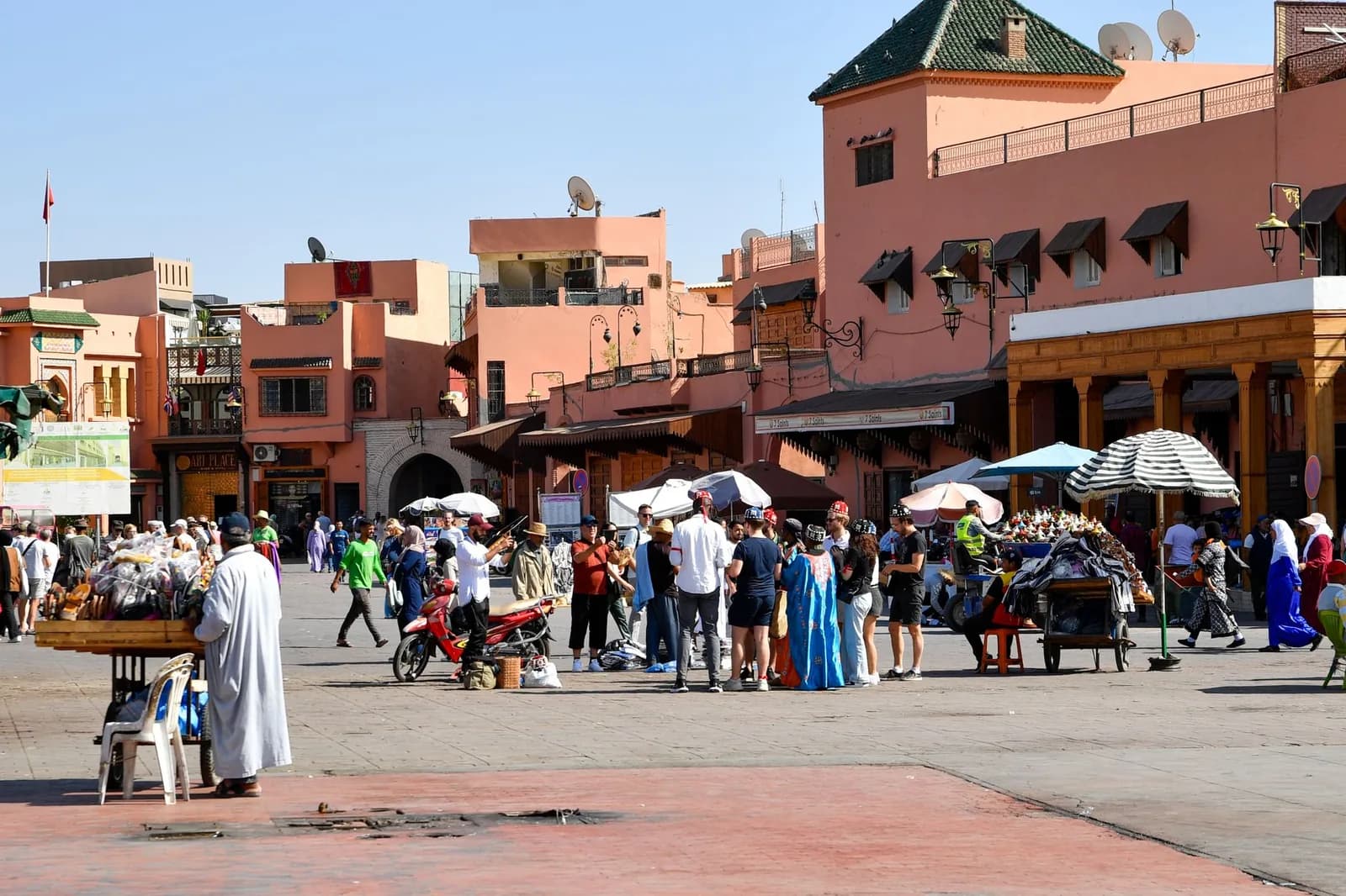 La place Jemaa el-Fna de Marrakech en journée, animée par les passants, les stands et les façades ocre