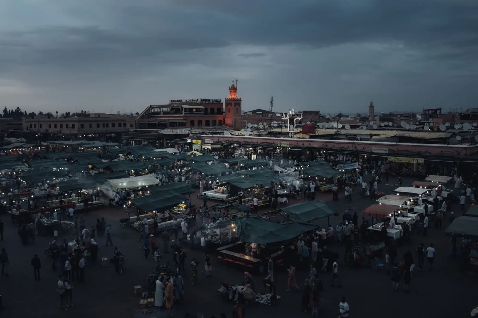 La place Jemaa el-Fna de Marrakech au crépuscule, ses food stalls illuminés et le minaret en arrière-plan
