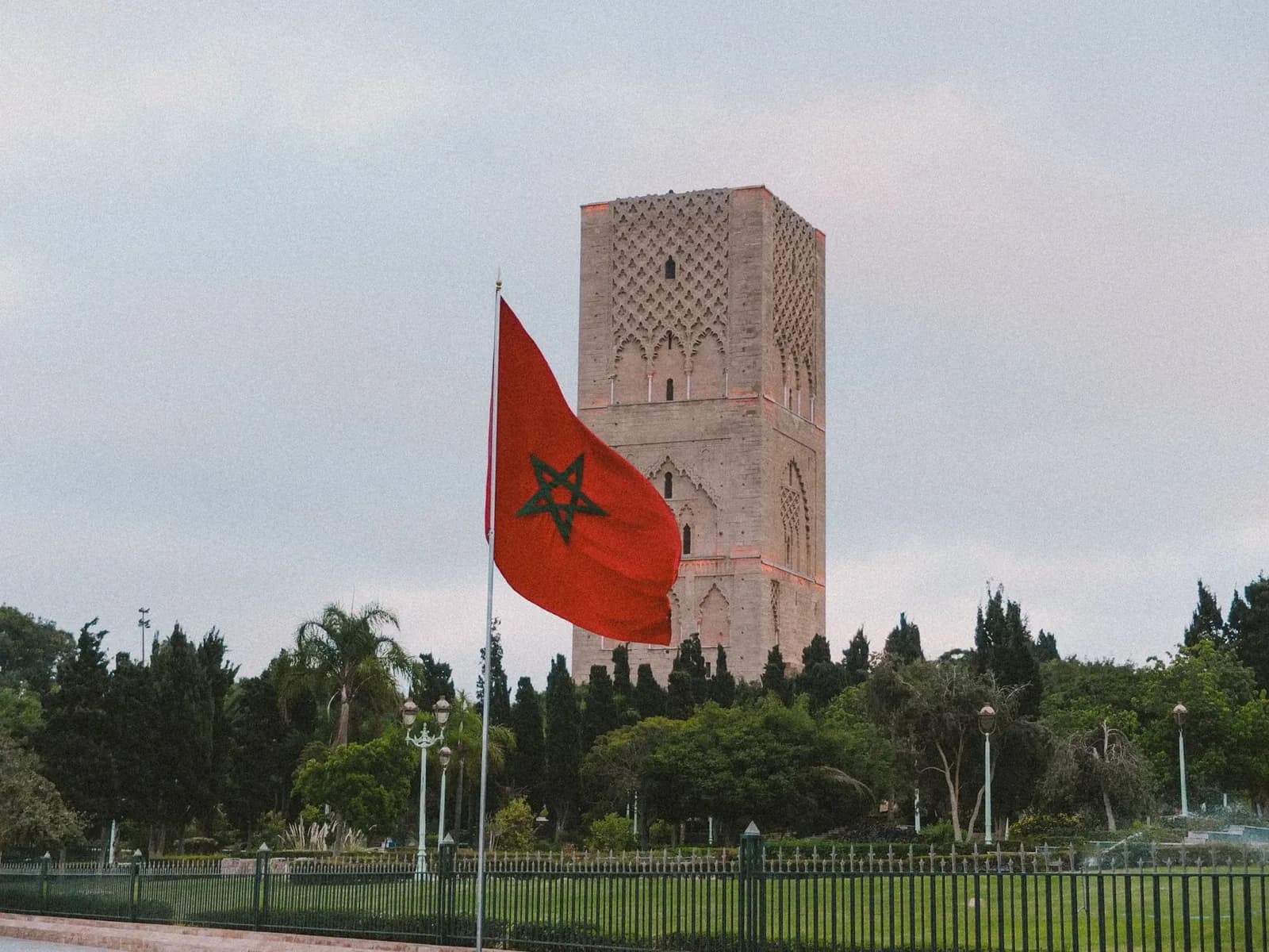 Drapeau marocain flottant devant la tour Hassan, à Rabat, dans un jardin arboré