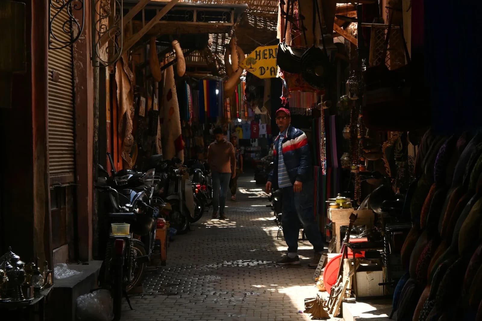 Ruelle de souk dans la médina de Marrakech, un volet métallique baissé et quelques passants
