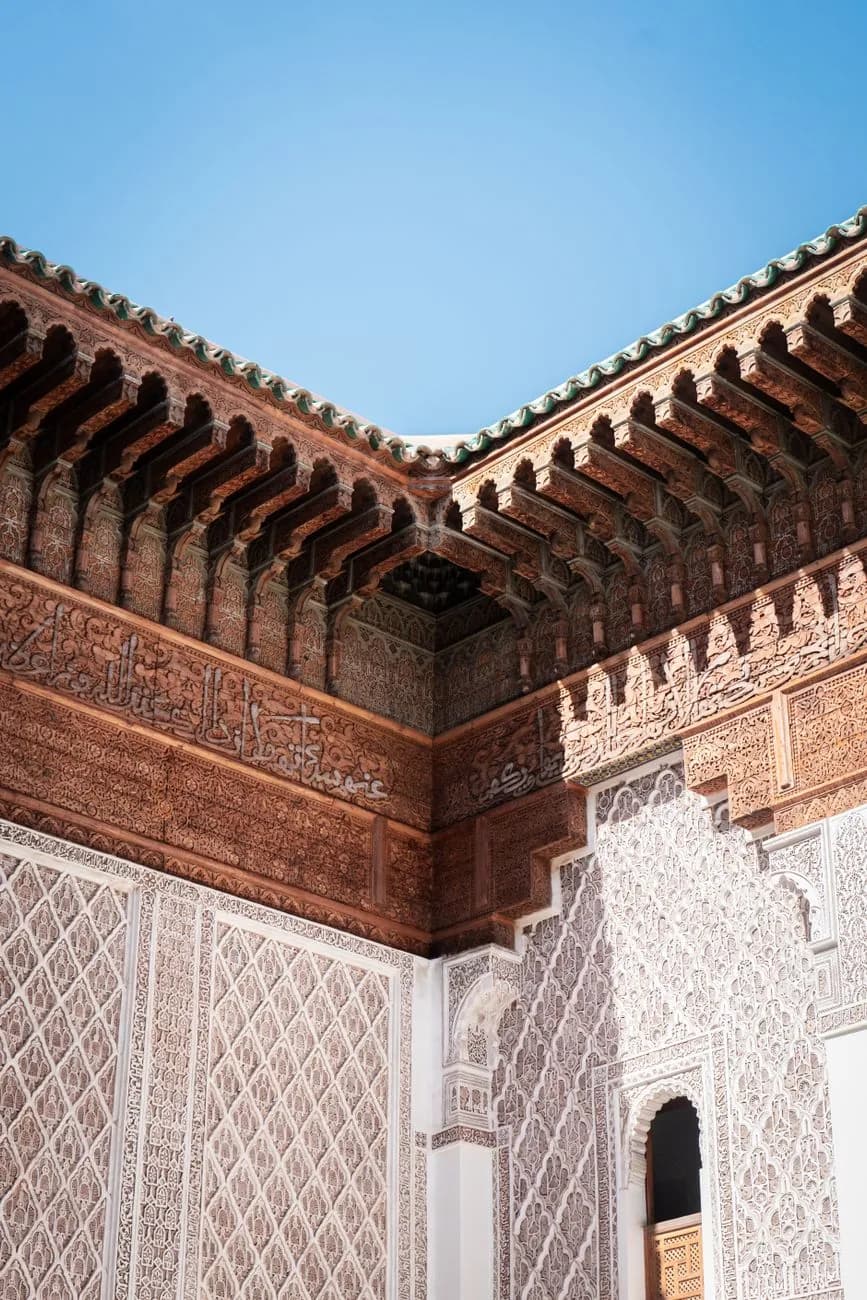 Corniche de cèdre sculpté et bandeau d'inscriptions coufiques au sommet de la cour de la Medersa Ben Youssef, Marrakech