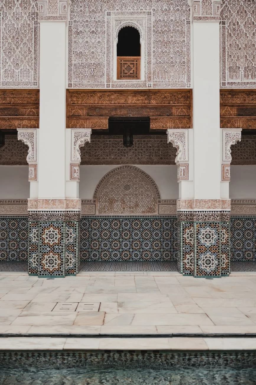 Zellige en étoiles, plâtre sculpté et linteau de cèdre dans une galerie de la Medersa Ben Youssef à Marrakech