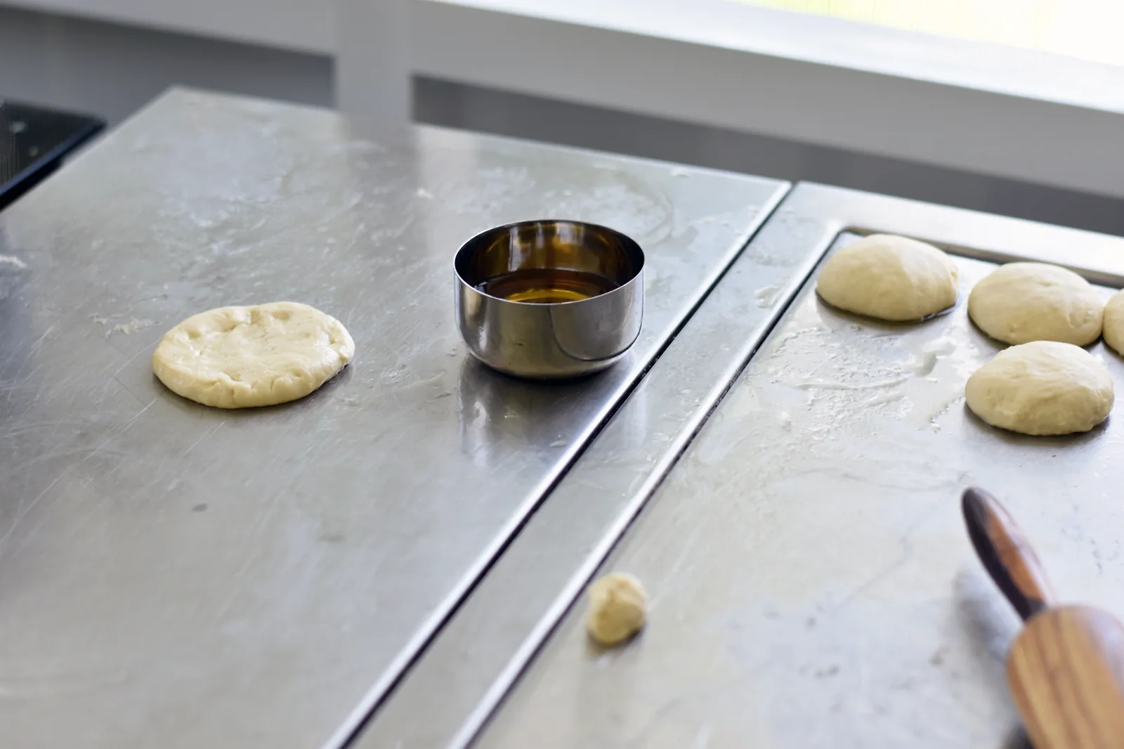 Boules de pâte à msemen huilées et alignées sur un plan de travail avant d'être étirées
