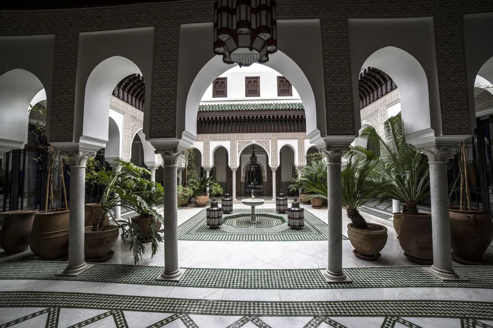 Patio de riad marocain avec colonnes, arcades et grande lanterne suspendue