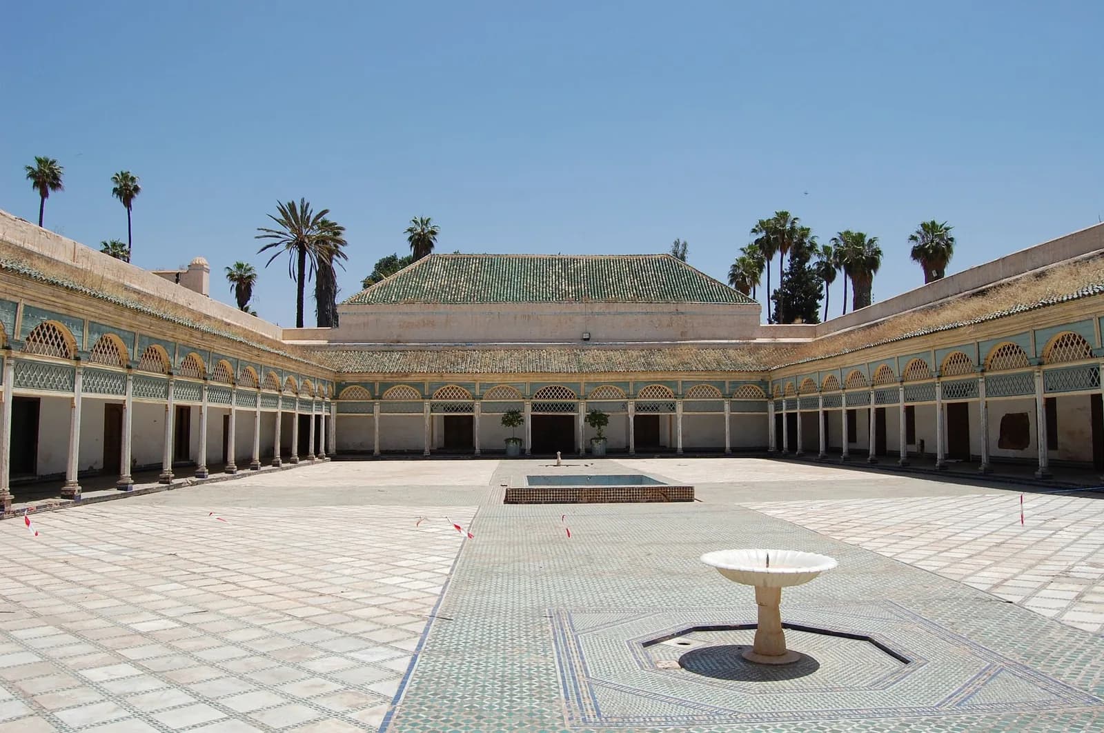 La grande cour d'honneur du Palais de la Bahia à Marrakech, entourée d'arcades et bordée de palmiers