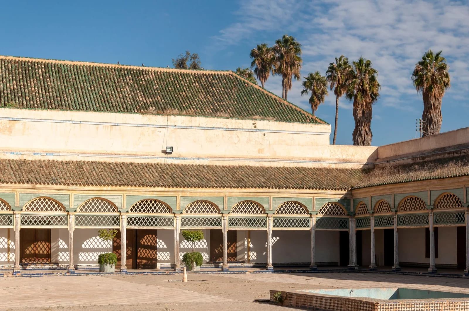 Arcades, colonnes et moucharabiehs bordant une cour du Palais de la Bahia à Marrakech, avec zellige au sol