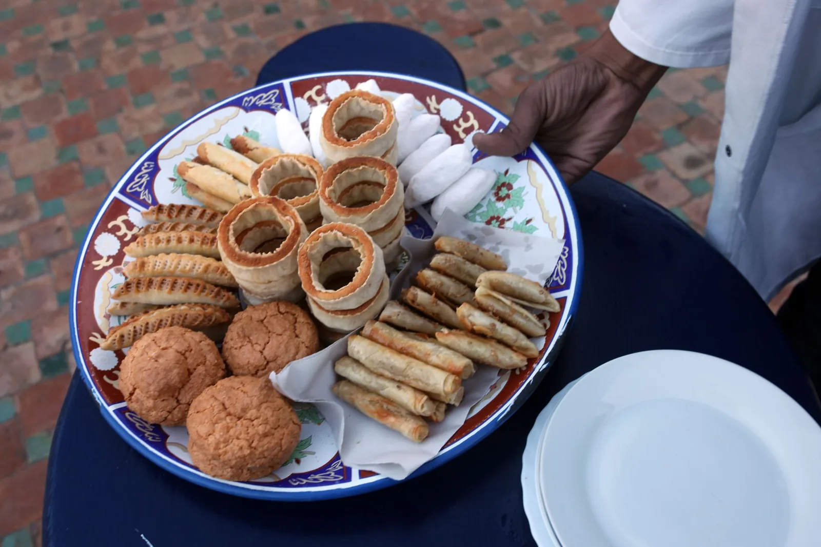 Grand plateau de pâtisseries marocaines, feqqas, briouat et ghriba, servi sur une table à Marrakech