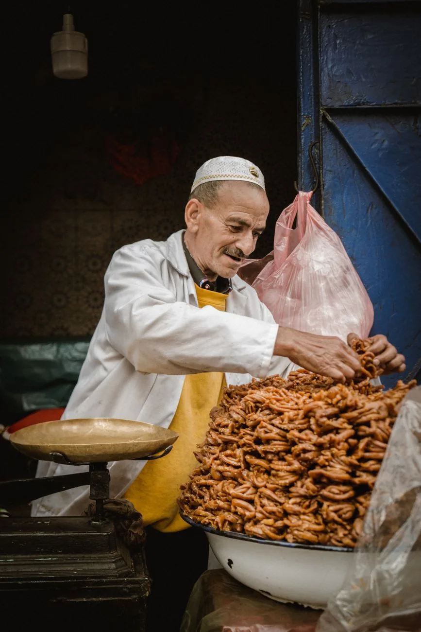 Marchand pesant des pâtisseries marocaines au miel à la balance dans un souk de Marrakech