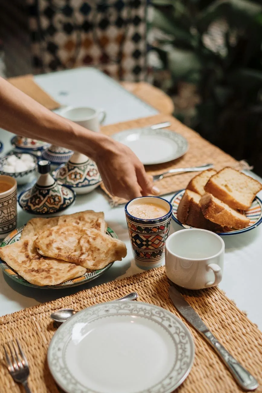 Msemen dorés servis dans une assiette en céramique marocaine avec un verre à thé et du pain