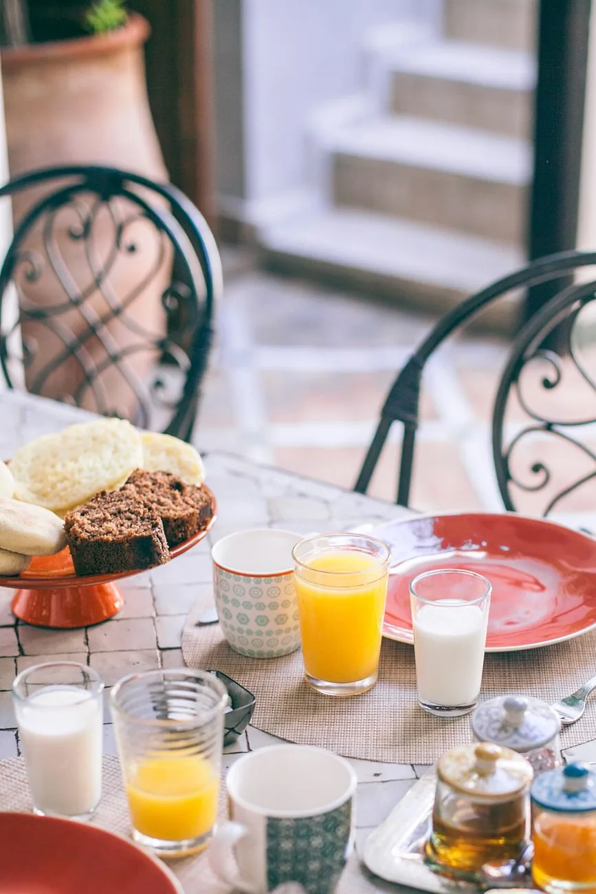 Petit déjeuner servi dans le patio d'un riad de Marrakech avec baghrir, jus d'orange et pot de miel