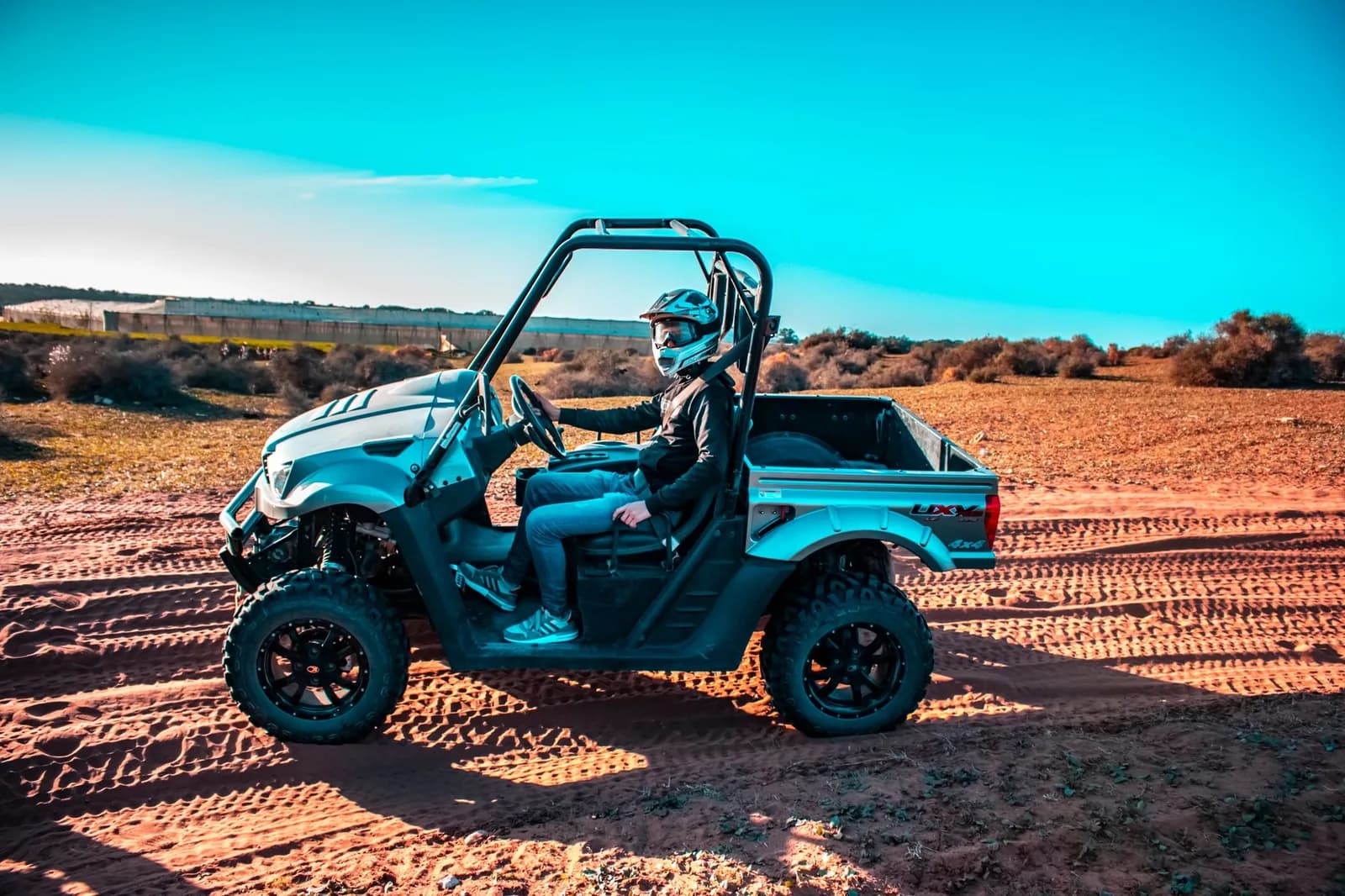 Buggy tout-terrain avec un pilote casqué sur une piste de terre rouge
