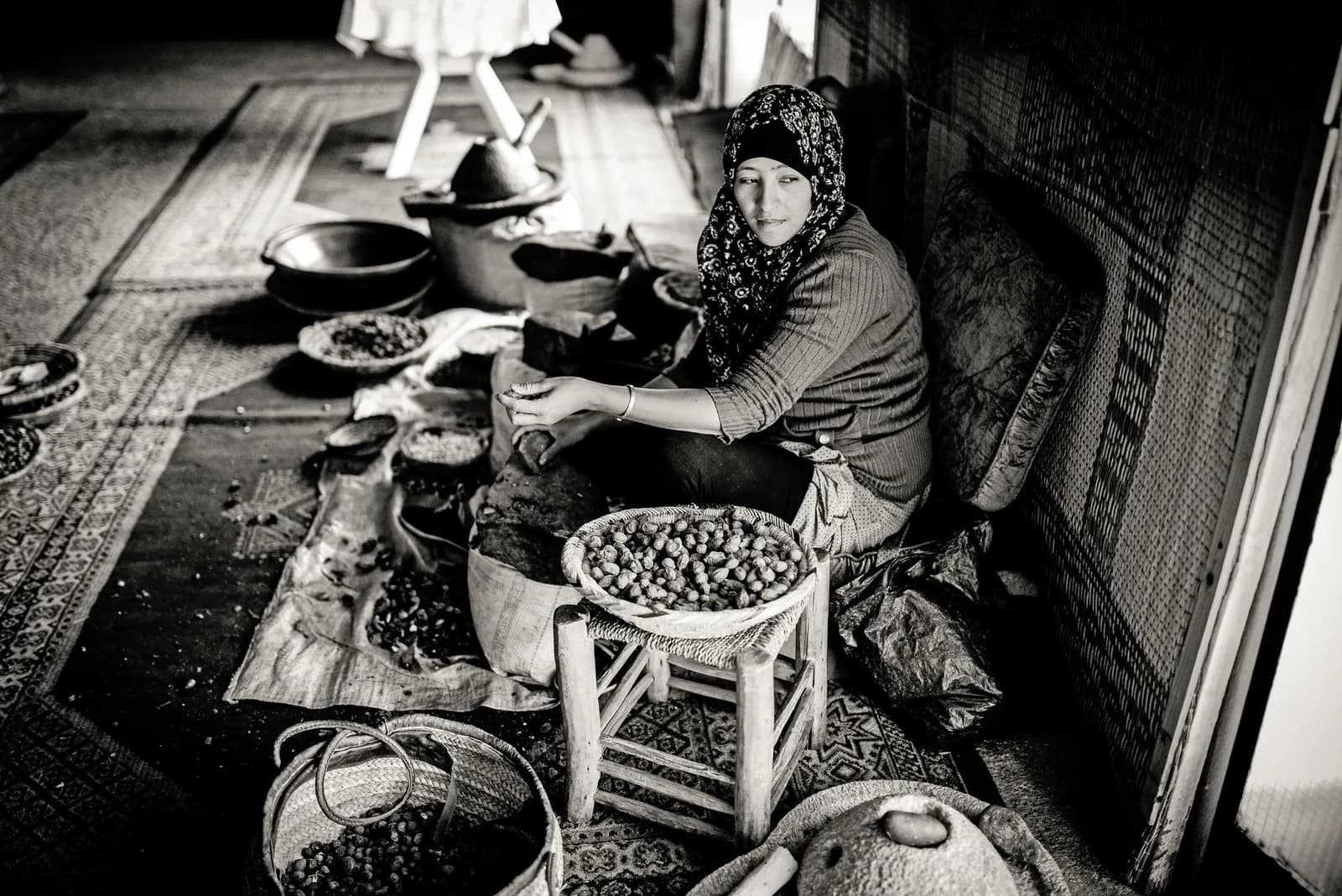 Femme d'une coopérative marocaine concassant des noix d'argan à la pierre pour en extraire l'huile
