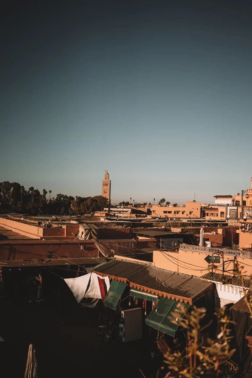 Vue depuis un rooftop de la médina de Marrakech sur les toits ocre et le minaret de la Koutoubia au soleil couchant