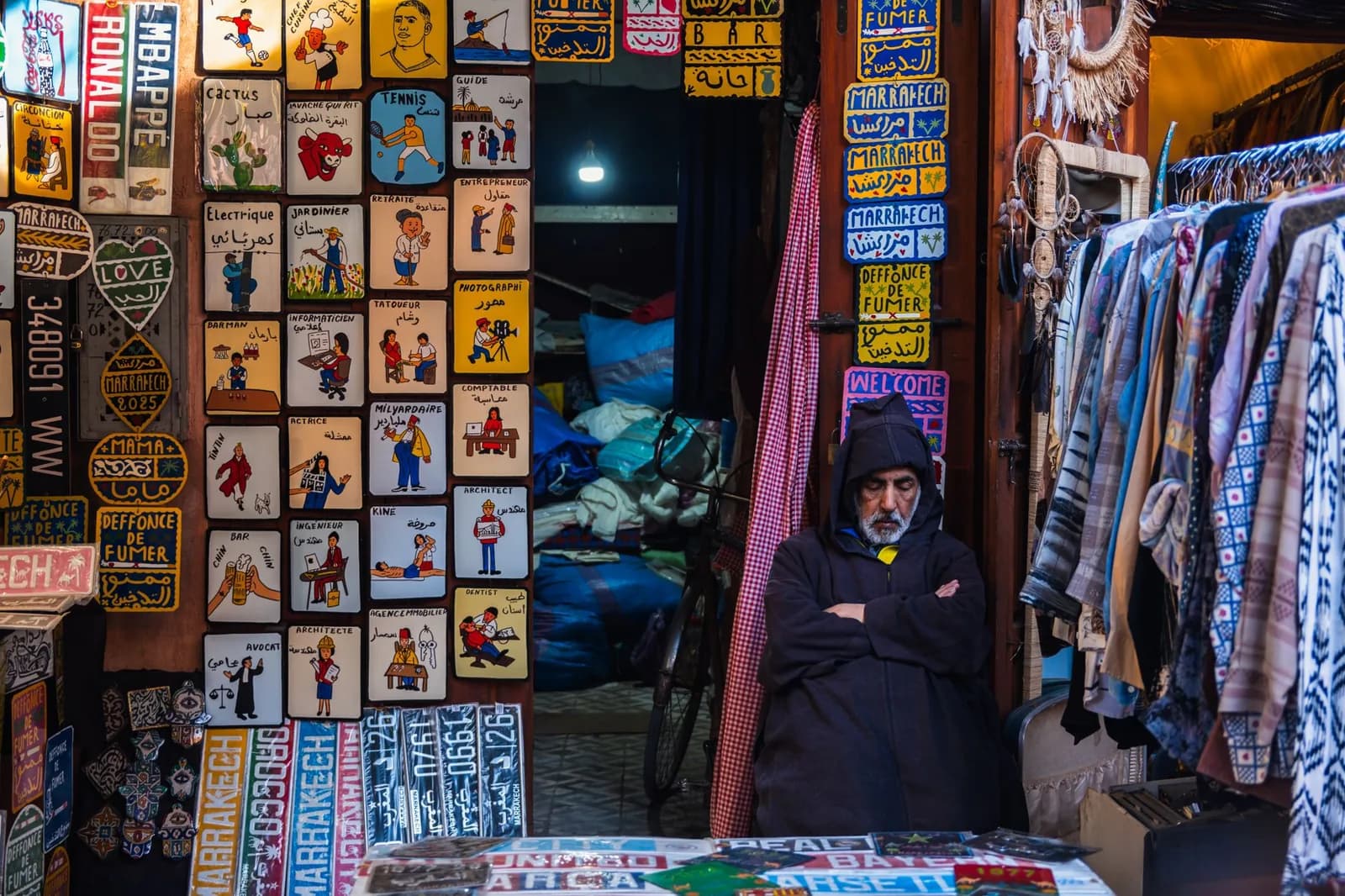 Commerçant devant sa boutique de souvenirs et de plaques peintes dans un souk de Marrakech