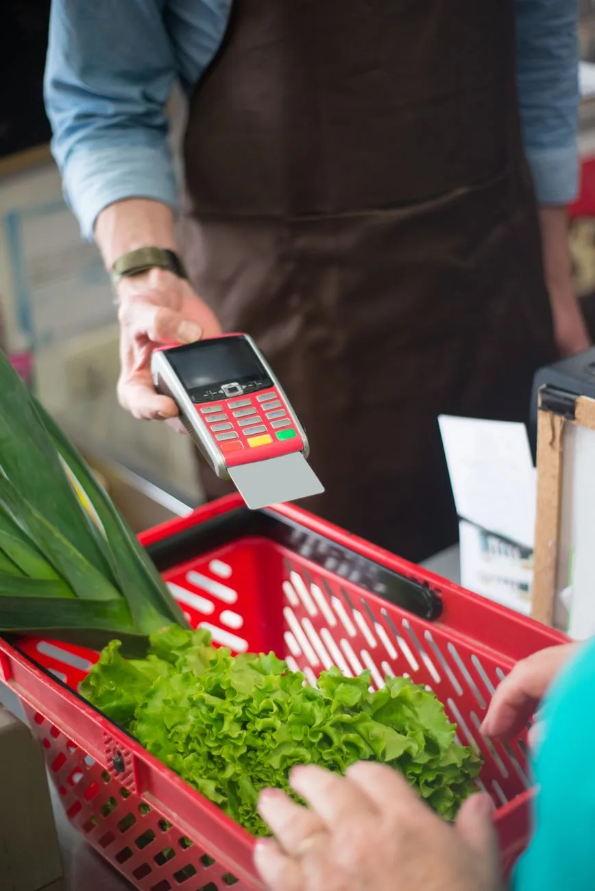Client qui règle ses courses par carte bancaire sur un terminal de paiement