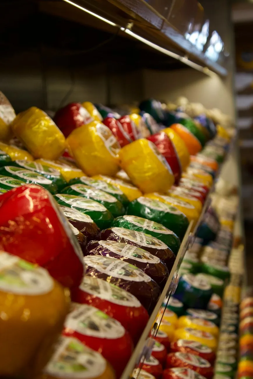 Rayon de fromages à croûte de cire rouge, jaune et verte dans un supermarché
