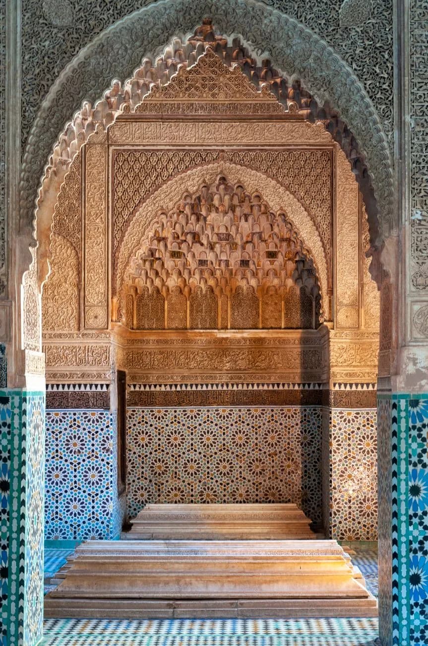 Niche à stalactites de stuc sculpté au-dessus d'une sépulture de marbre, murs de zellige, aux Tombeaux Saadiens de Marrakech