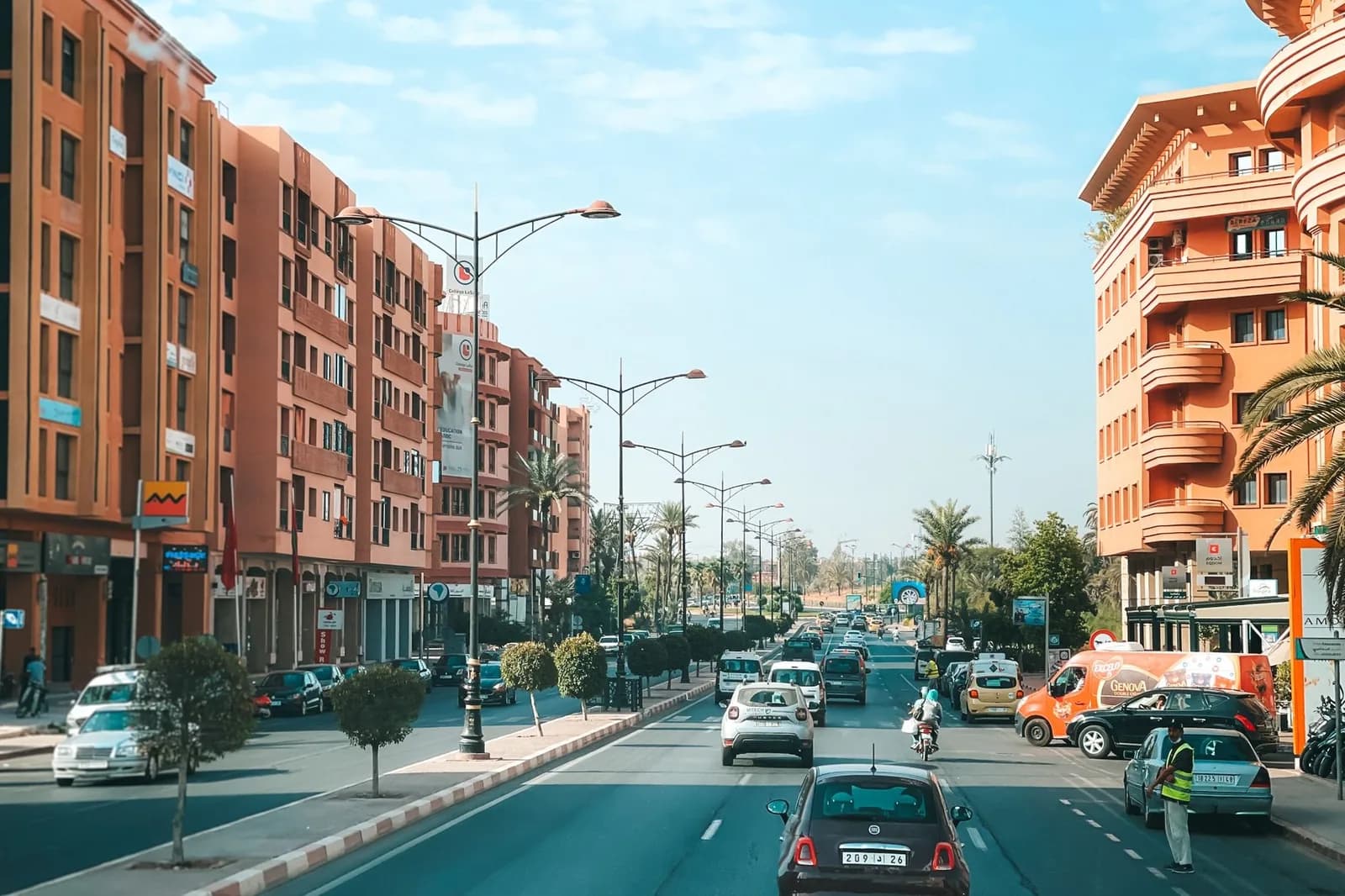 Grande avenue de la ville moderne de Marrakech, bordée d'immeubles ocre et de palmiers sous un ciel bleu