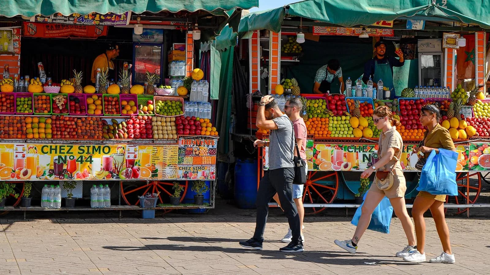 Stands de jus d'orange pressés et de fruits frais sur la place Jemaa el-Fna à Marrakech, bouteilles d'eau alignées sur les étals